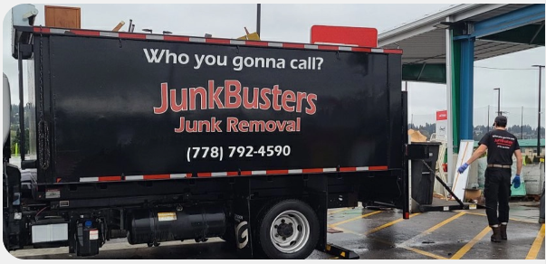 Black truck trailer with Junk Buster logo. Employee shown walking behind the truck. 