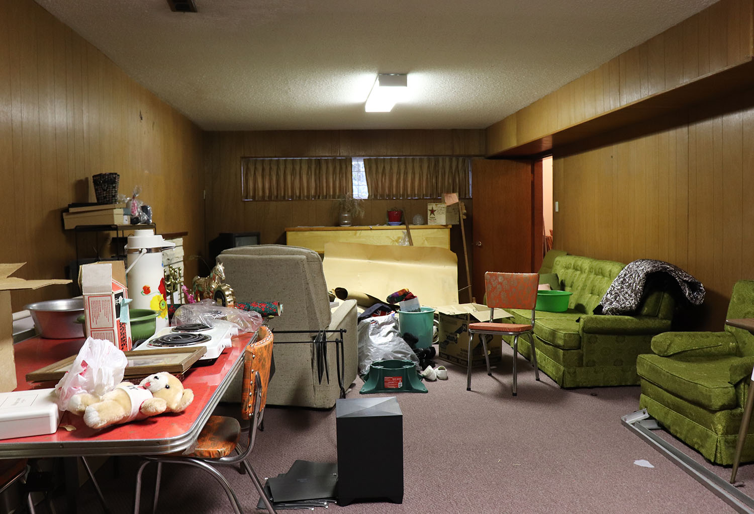 Garage full of junk including personal items and appliances. A partial view of a vehicle is also seen in the garage. 